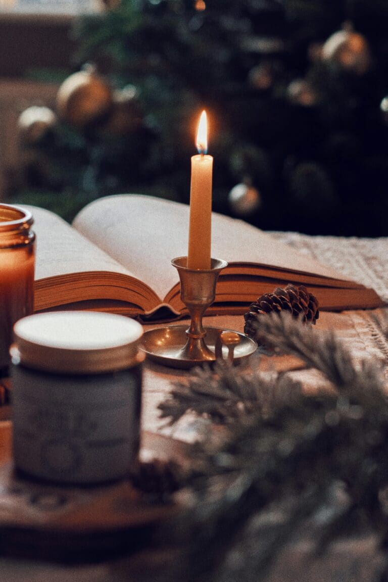 Warm scene with open book, lit candle, and festive decor, perfect for holiday season ambiance.